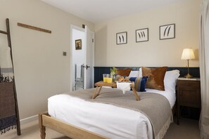 Ein ordentlich eingerichtetes Schlafzimmer mit Bett, Nachttisch, Lampe und Wandbild.