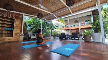 Un estudio de yoga con suelo de madera, colchonetas azules y una estantería de madera.