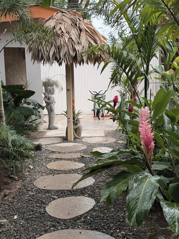 Un sendero en el jardín con piedras que conducen a una construcción de paja.