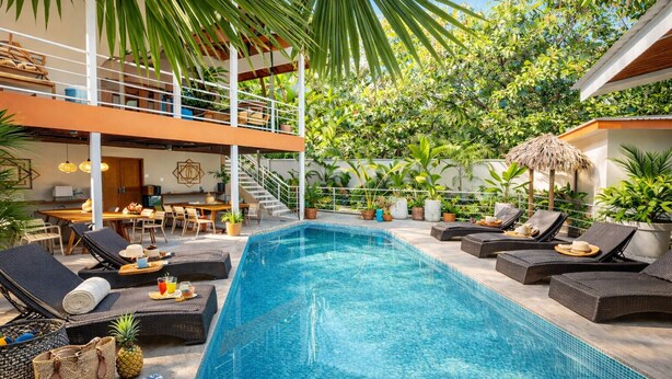 A swimming pool with lounge chairs and a dining area.