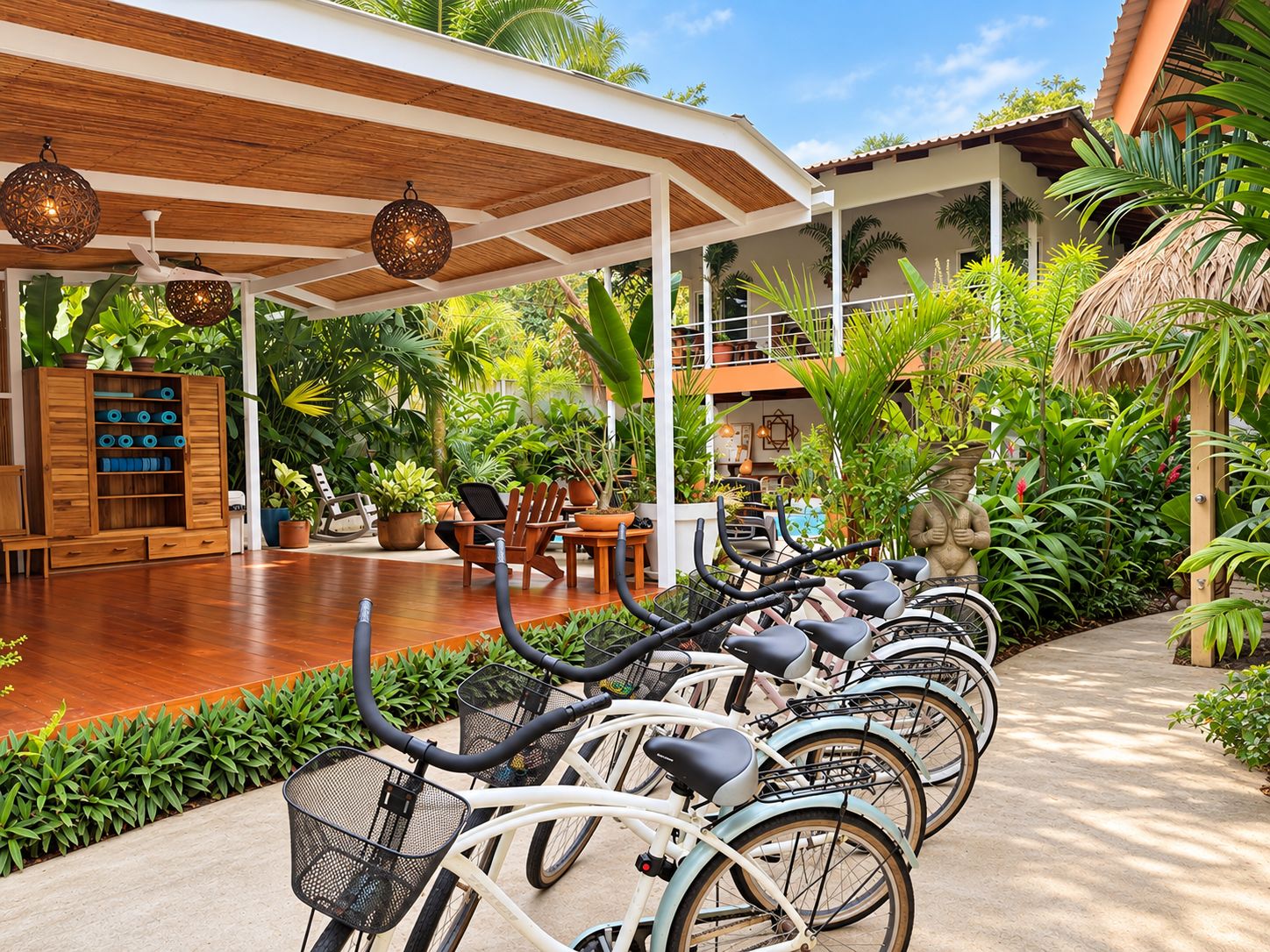 Un espace extérieur abrité comprenant une rangée de vélos, un coin salon avec des chaises et diverses plantes en pot.