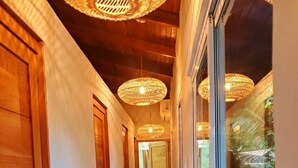 A hallway with wooden doors, a tiled floor, and woven ceiling lights.