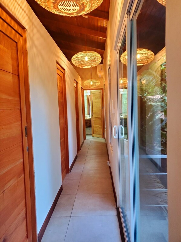 A hallway with wooden doors, a tiled floor, and woven ceiling lights.