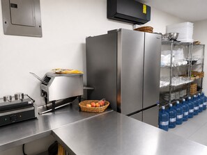 Cocina de acero inoxidable con microondas integrado, cafetera y dispensador de agua.