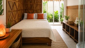 A bedroom with a bed, wooden headboard, ceiling fan, potted plants, and a glass door leading to a balcony.