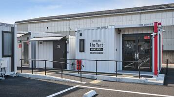 L’entrée d’un hôtel au design moderne, comprenant un comptoir d’accueil et une enseigne indiquant « The Yard », qui fait partie du groupe R9 Hotels.