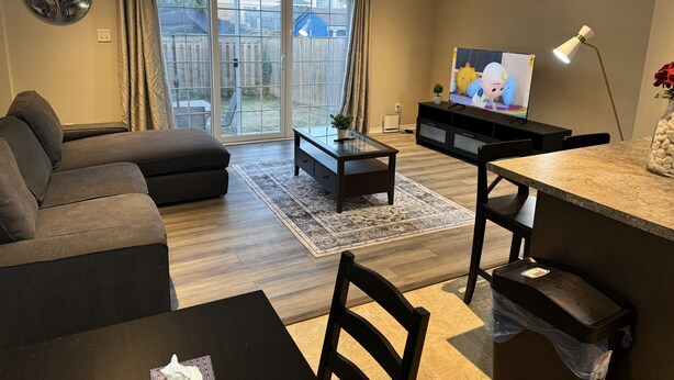A living room with a sofa, a coffee table, a TV, and a dining area with a table and chairs.