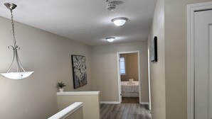 A hallway with a wooden floor, a white door, and a painting on the wall.
