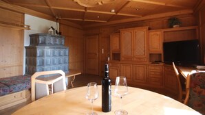 Interior de madeira com uma mesa de jantar, dois copos de vinho, uma garrafa e uma televisão.