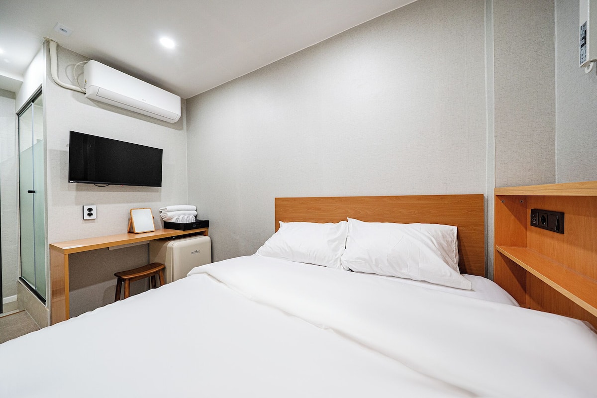 Ein Hotelzimmer mit Bett, Schreibtisch, Fernseher und Klimaanlage.