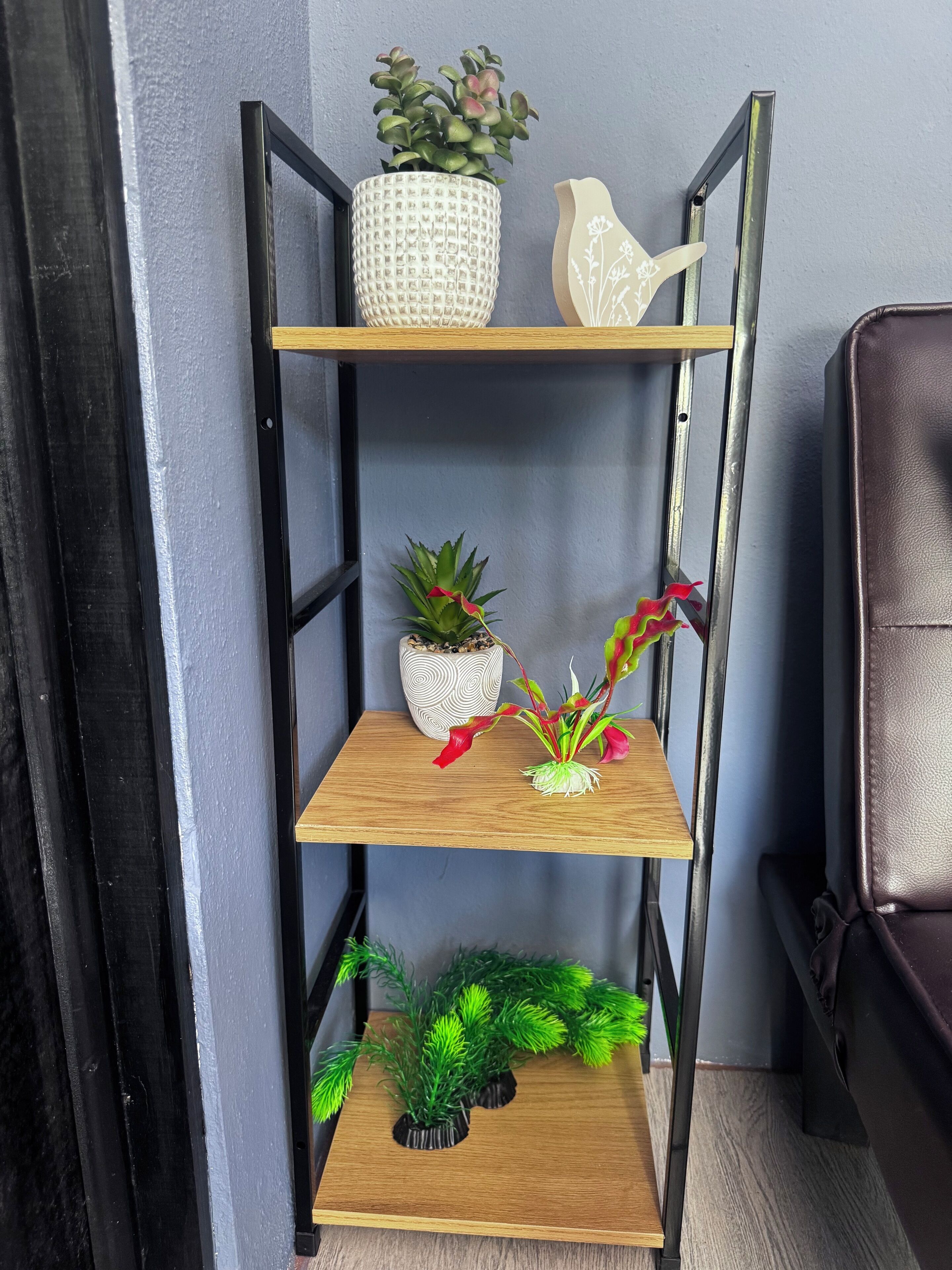 A wooden shelf unit with three levels, each holding different decorative items.