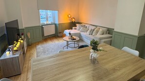 Ein gemütliches Wohnzimmer mit einem Holzesstisch, einer Couch und einem Fernseher.