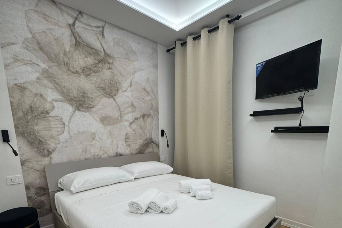 A modern bedroom with a bed, a flat-screen TV, and a stone-patterned wall.
