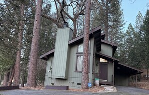 A cabin with a sloped roof, a chimney, and a small porch.