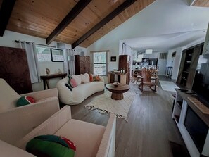 Ein Wohnzimmer mit einer Couch, Sesseln, einem Couchtisch und einem Fernseher.