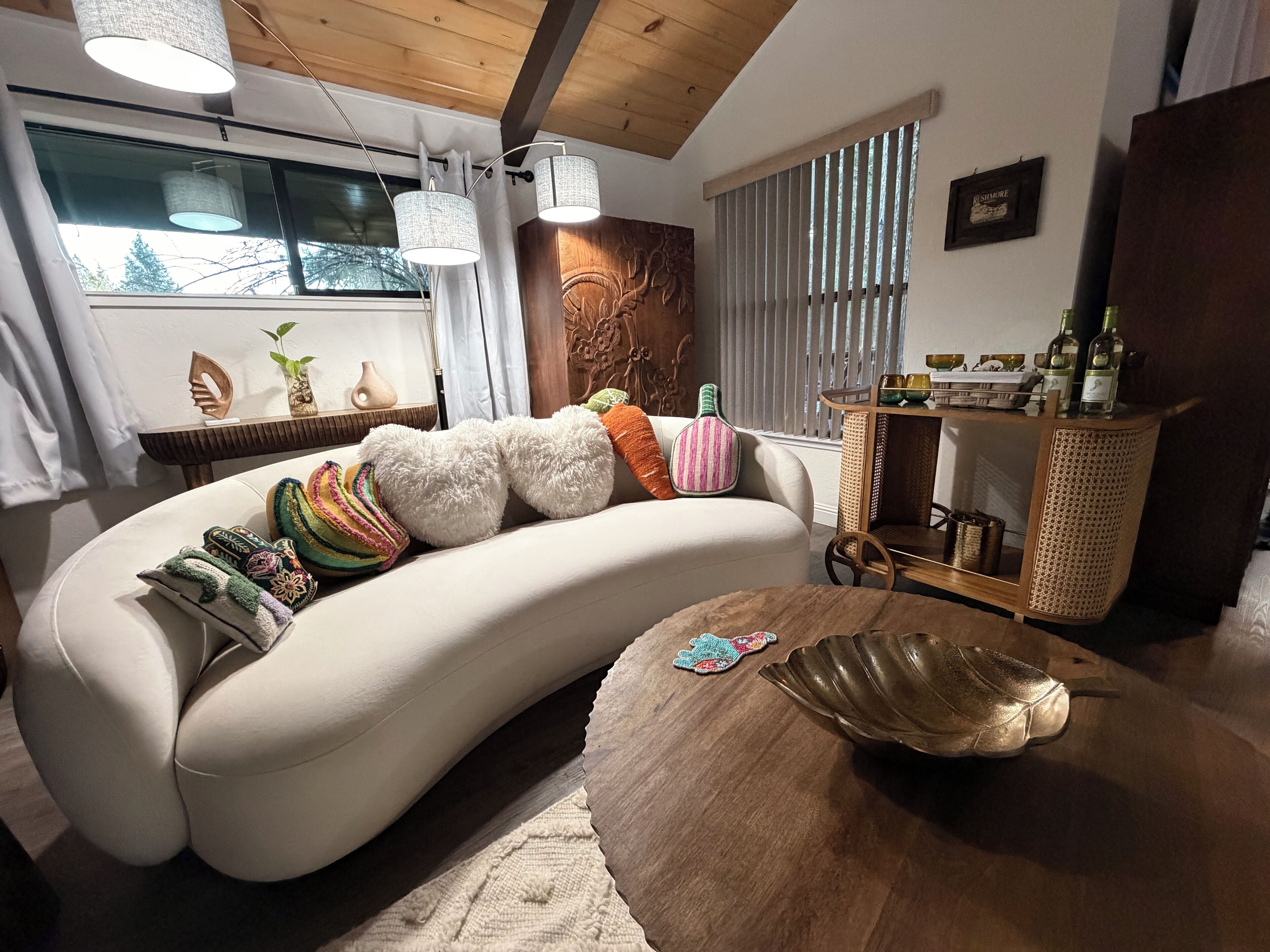 Un salon moderne avec un canapé aux lignes courbes, une table basse en bois et un élément décoratif mural.