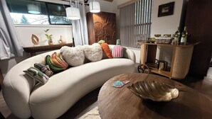 A modern living room with a curved sofa, a wooden coffee table, and a decorative wall piece.