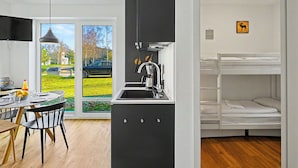 A modern kitchen with a sink, a dining area with a table and chairs, and a view of the outside.