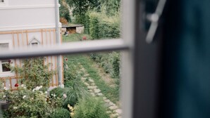 A view from a window of a building with a garden in front, including a pathway and various plants. - Quiet apartment above the Bobertal valley in the foothills of the Giant Mountains (Tarczyn)