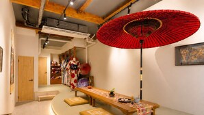 Una habitación con una larga mesa de madera, un paraguas rojo y decoración japonesa tradicional.