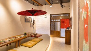 Una habitación tradicional japonesa con esteras de tatami, una mesa de madera baja, un paraguas rojo y puertas correderas.