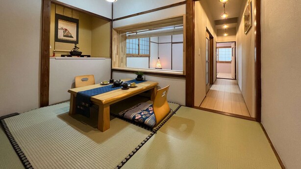 Una habitación tradicional japonesa con suelo de tatami, un escritorio de madera bajo y una puerta corredera de shoji.