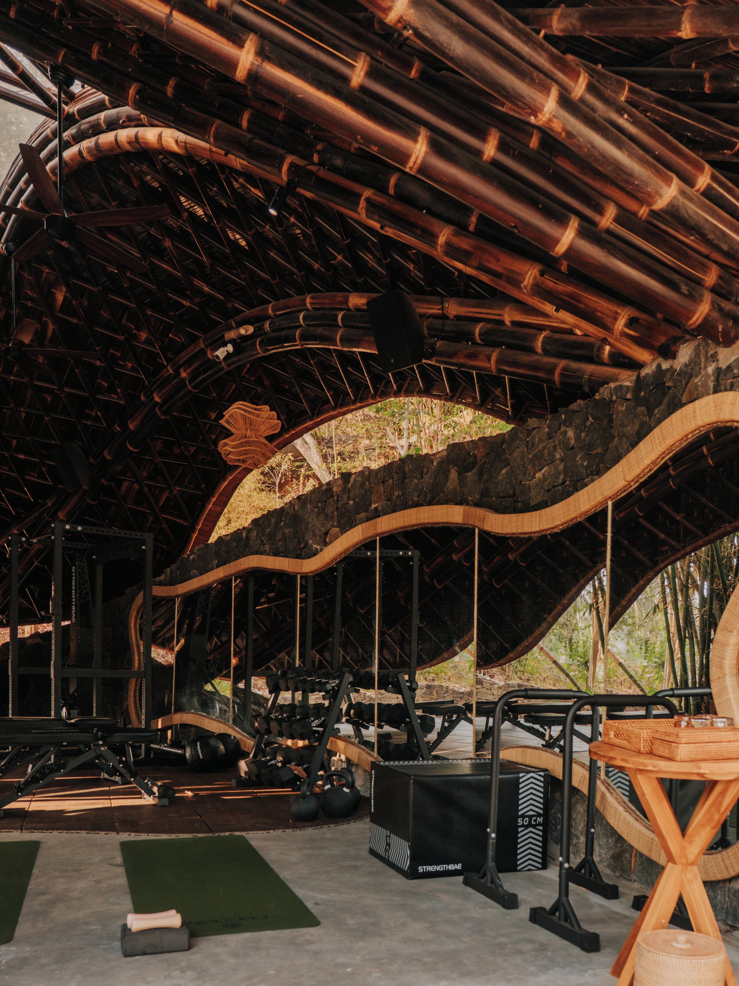 A gym with exercise equipment, a large wooden arch structure, and a concrete floor.