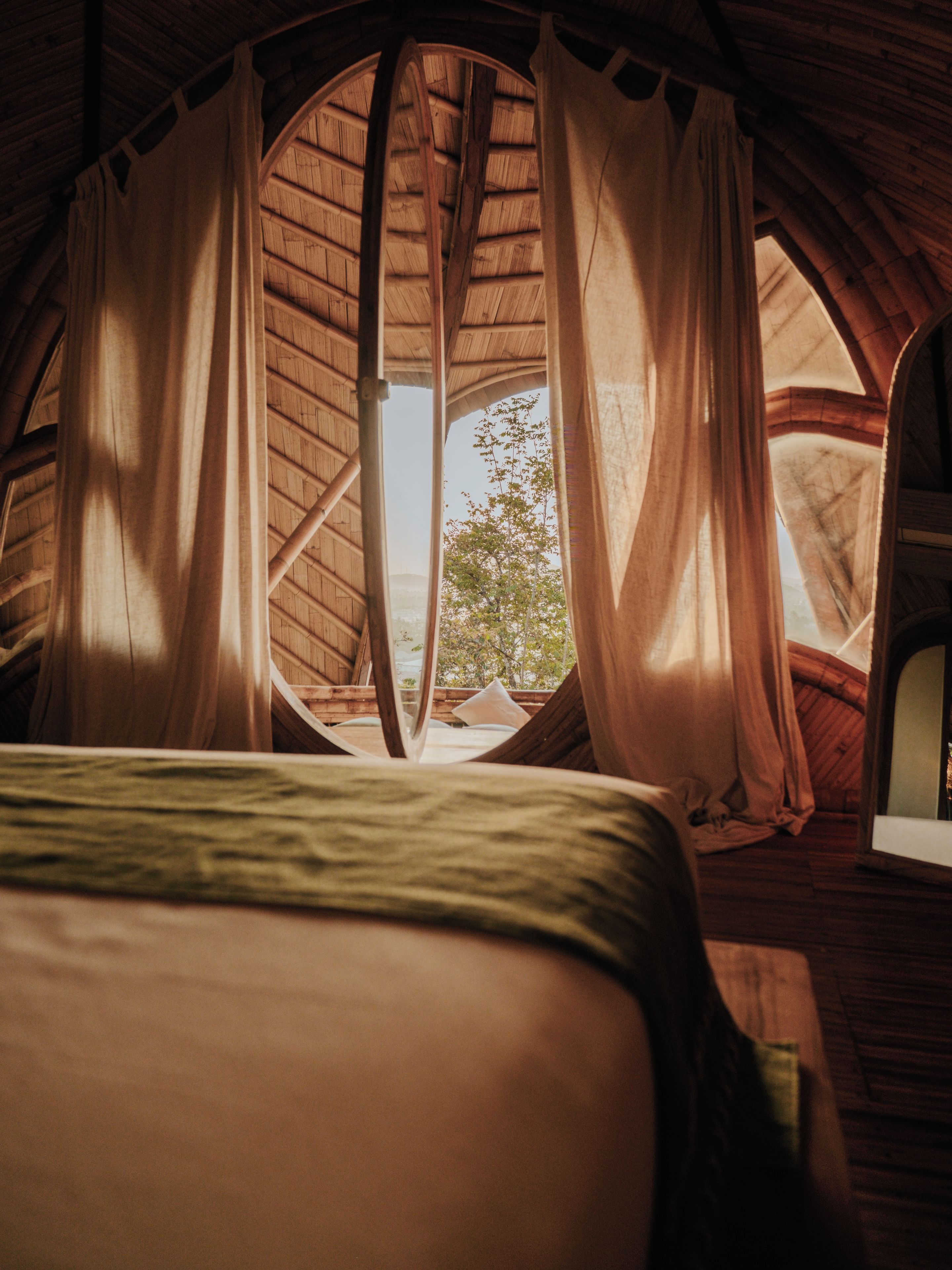 Une pièce confortable avec un lit, des murs en bois et une grande fenêtre avec des rideaux.