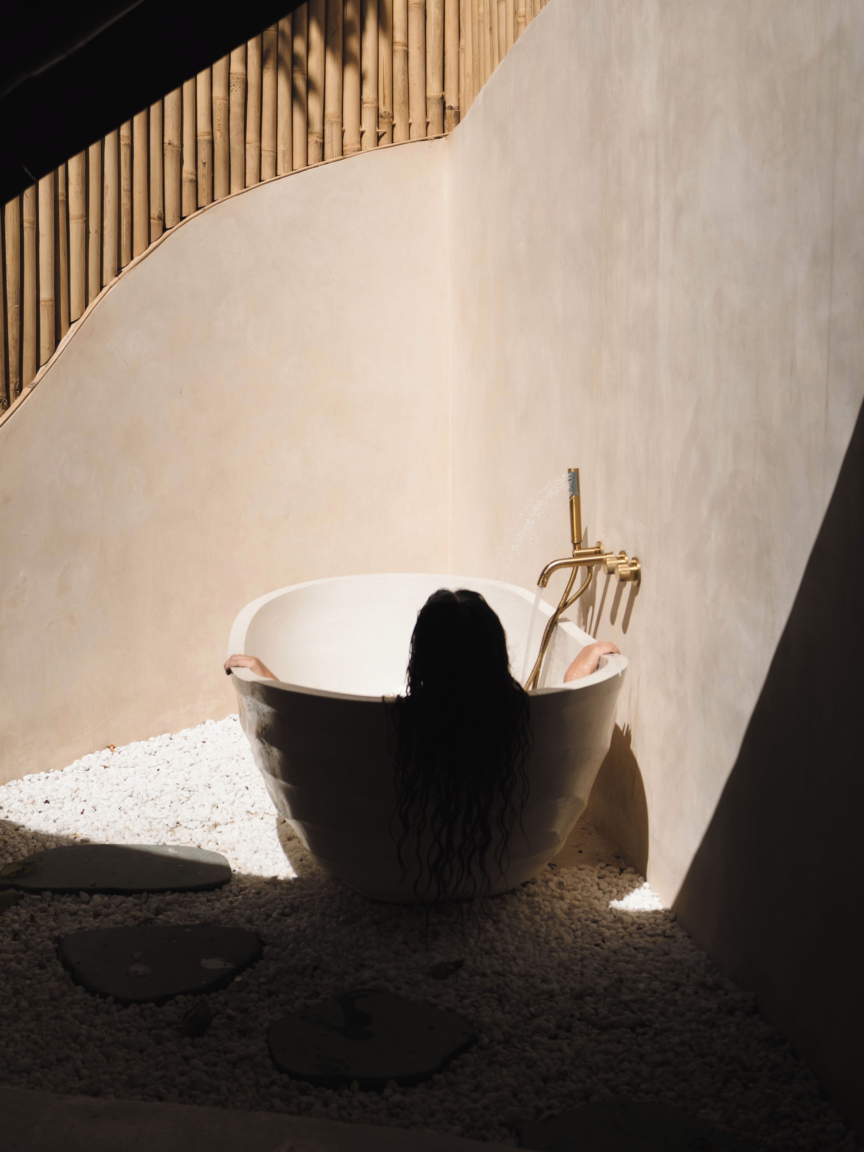 A bathtub in a corner with a wooden slat wall behind it.
