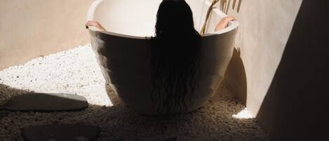 A bathtub in a corner with a wooden slat wall behind it.