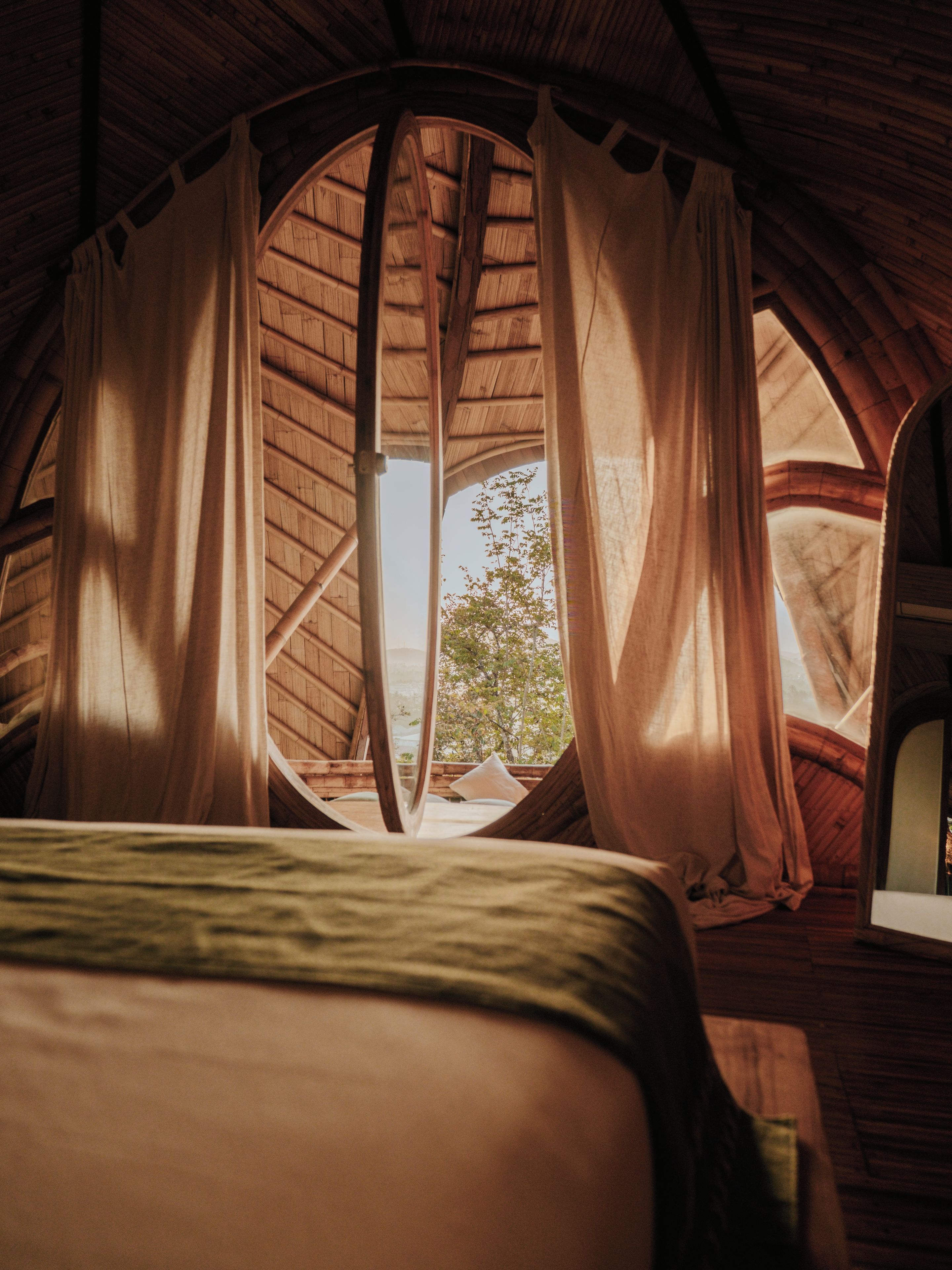 Une pièce chaleureuse avec un plafond voûté, des poutres en bois et un lit recouvert d’une couverture verte.