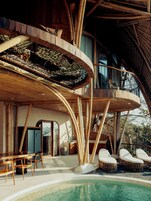 A modern villa with a pool, outdoor seating, and a unique bamboo structure.