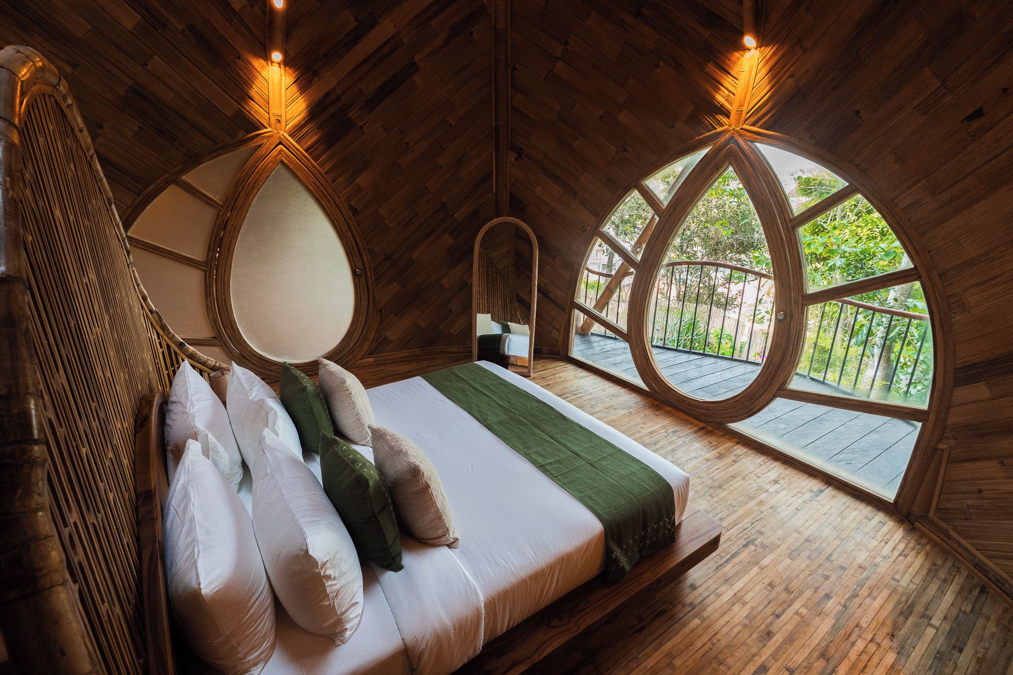 Une chambre à coucher en bois avec un lit, un fauteuil suspendu et une grande fenêtre circulaire.