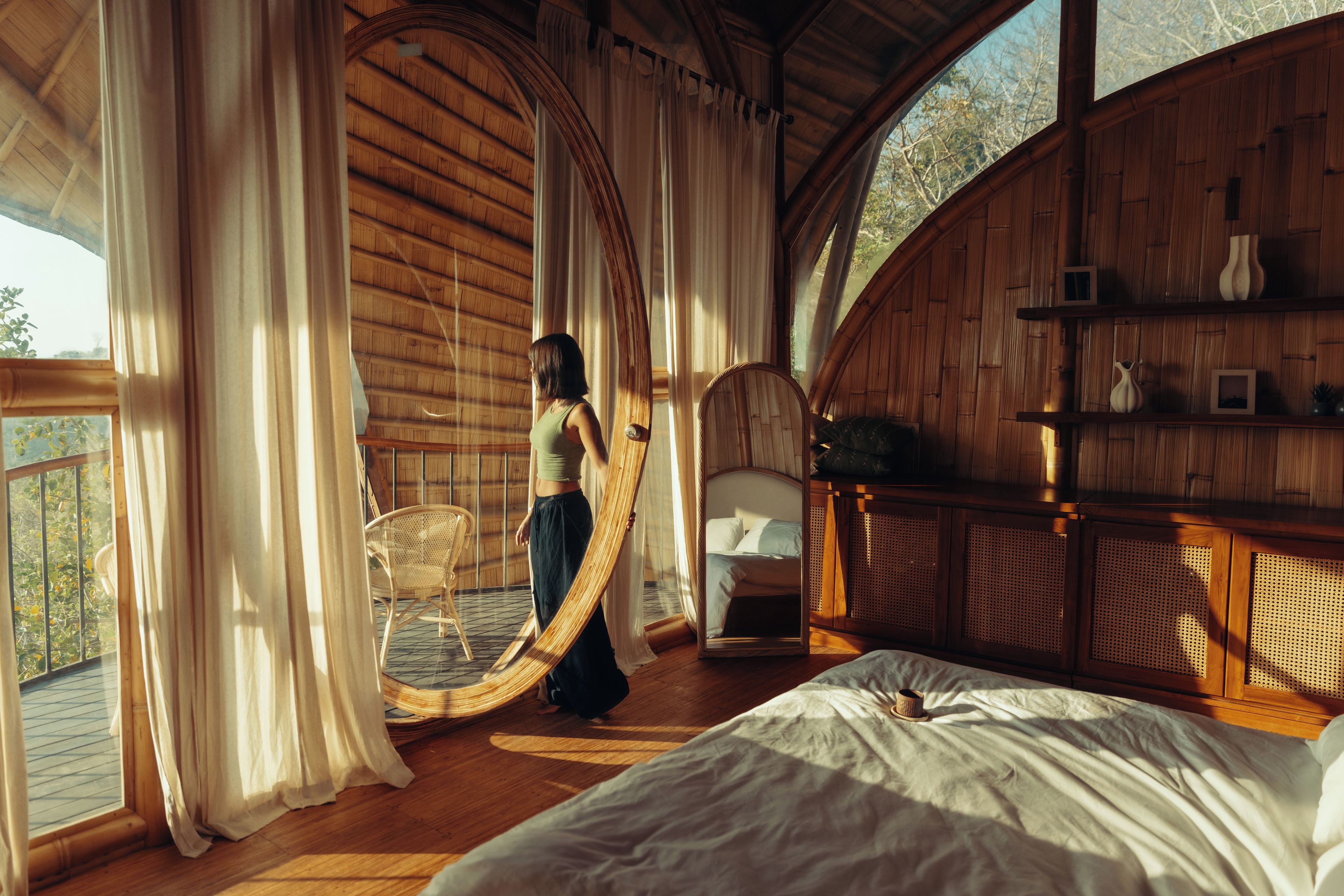 Una habitación con cama, una silla y un espejo grande.
