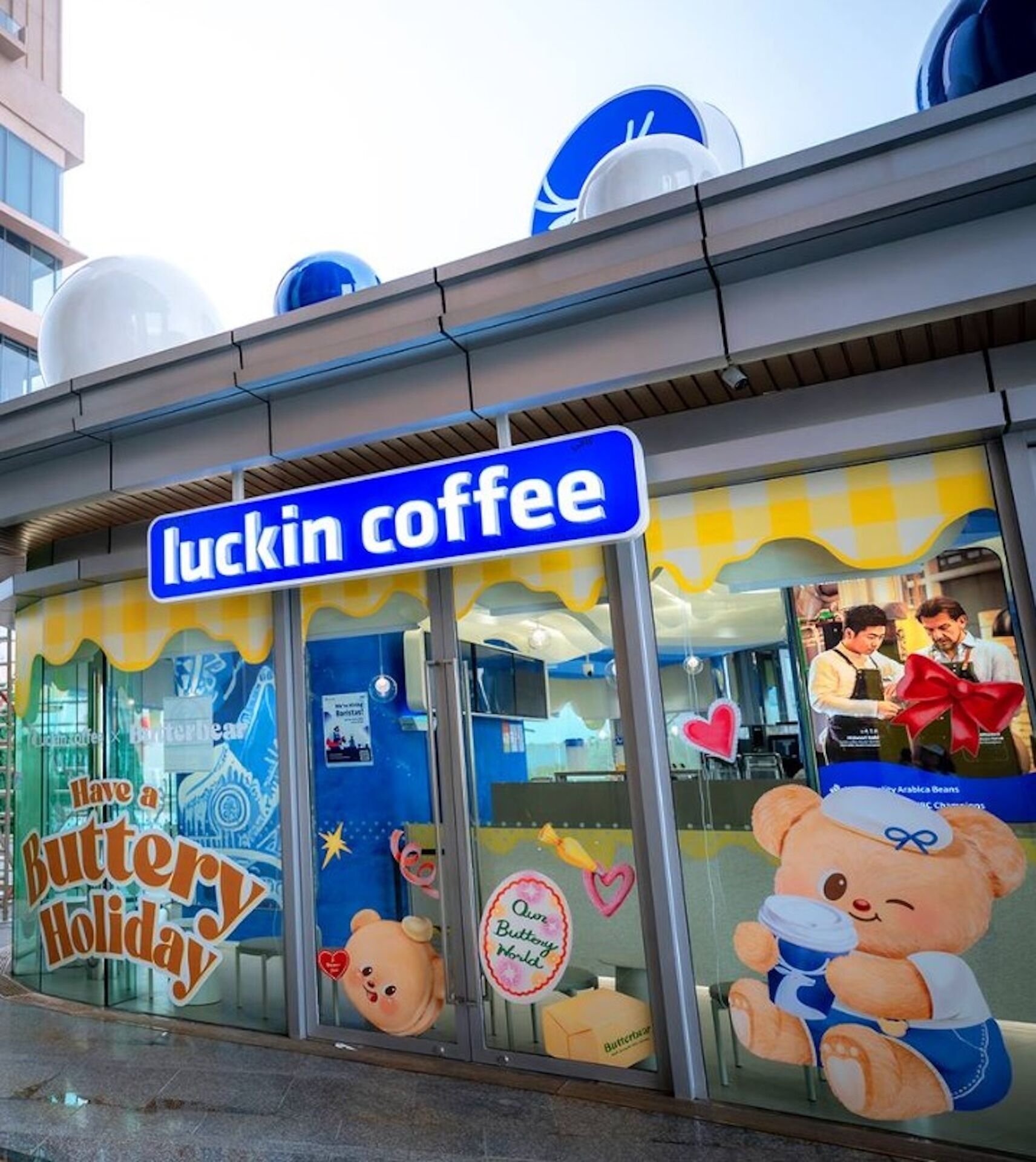 A storefront with a sign reading "luckin coffee" and a bear mascot outside.