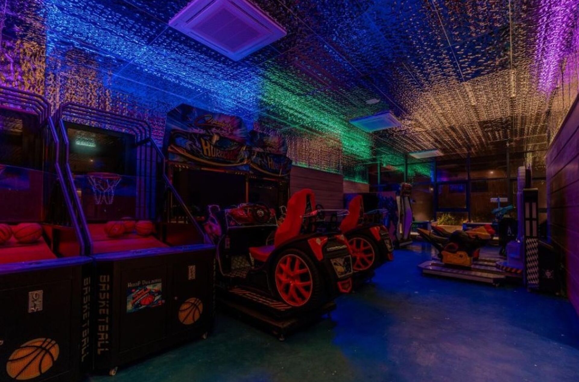 A dimly lit room with a basketball theme, featuring a basketball hoop, a car-shaped couch, and a wall with a basketball court design.