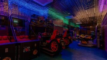 A dimly lit room with a basketball theme, featuring a basketball hoop, a car-shaped couch, and a wall with a basketball court design.