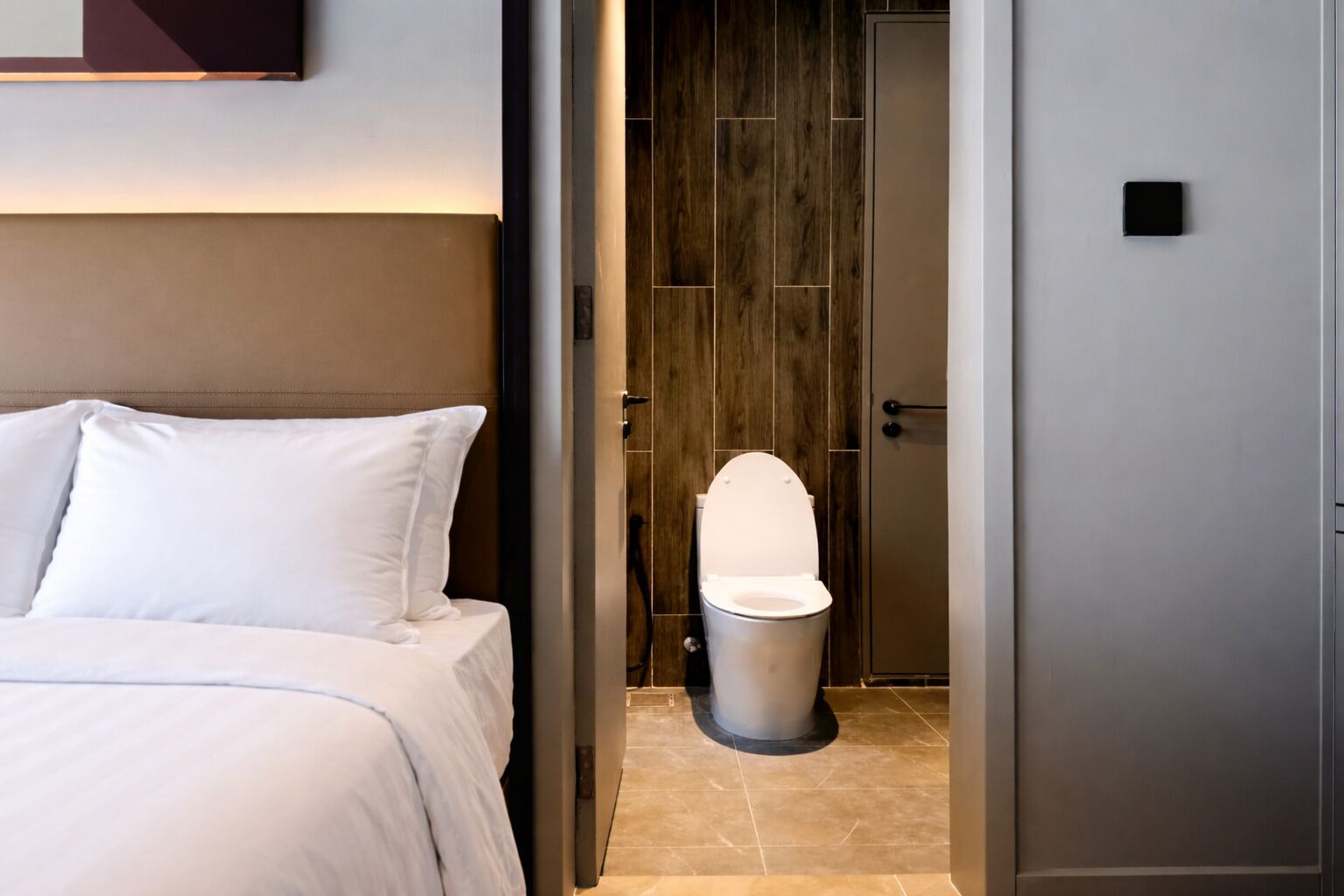 A hotel room with a bed, a toilet, and a door.