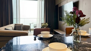 Ein modernes Hotelzimmer mit Essbereich, einer Couch, einem Fernseher und Blick auf die Stadt.