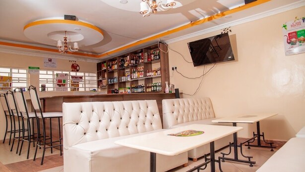 Un restaurant doté d’un bar, de sièges confortables et d’un téléviseur fixé au mur.