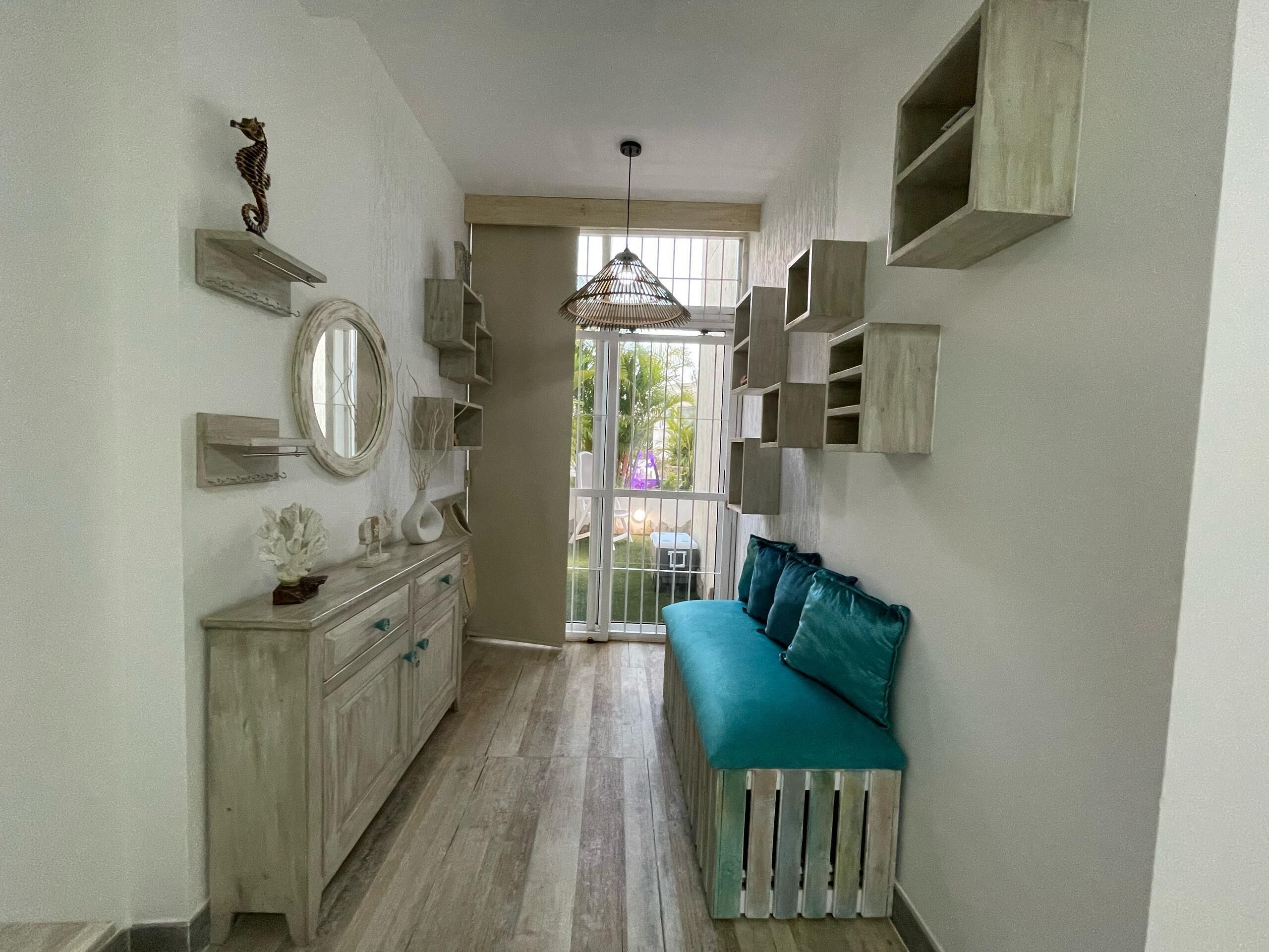 A narrow hallway with a bench, a mirror, and a seahorse decoration.