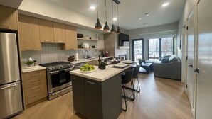 A modern kitchen with a central island, stainless steel appliances, and pendant lighting. - Bell`s Butte | Pool, Hot Tub & Fitness | Parking (Canmore)