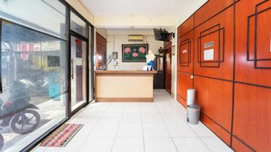A reception area with a counter, a wall-mounted TV, and a framed picture of flowers. - Guesthouse Pondok Tamsis by ARBA (Yogyakarta)