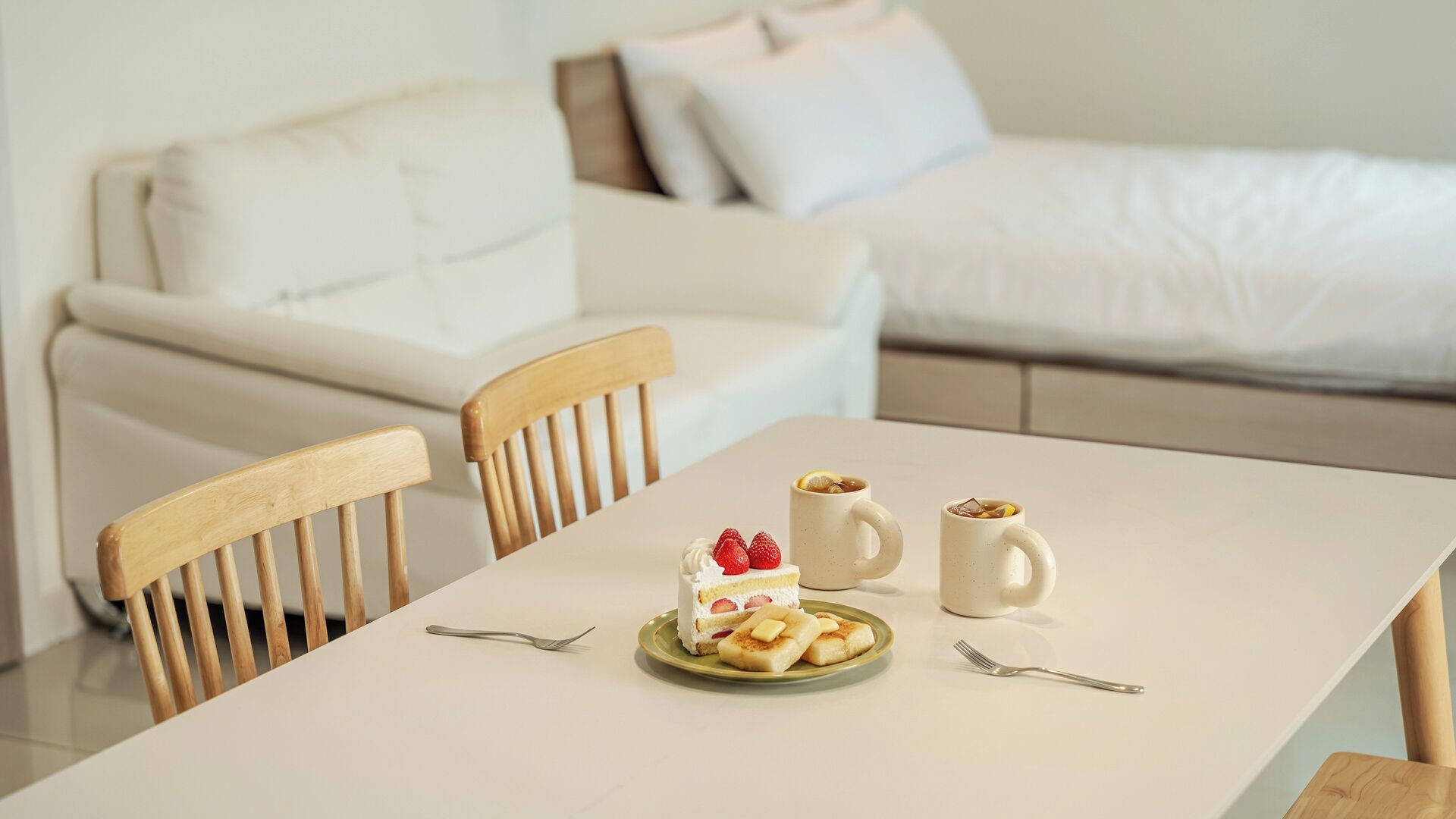 A dining table with a plate of food, two mugs, and cutlery.