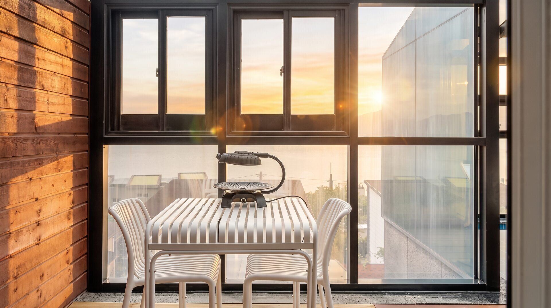 A room with a large window, a table with chairs, and a lamp.