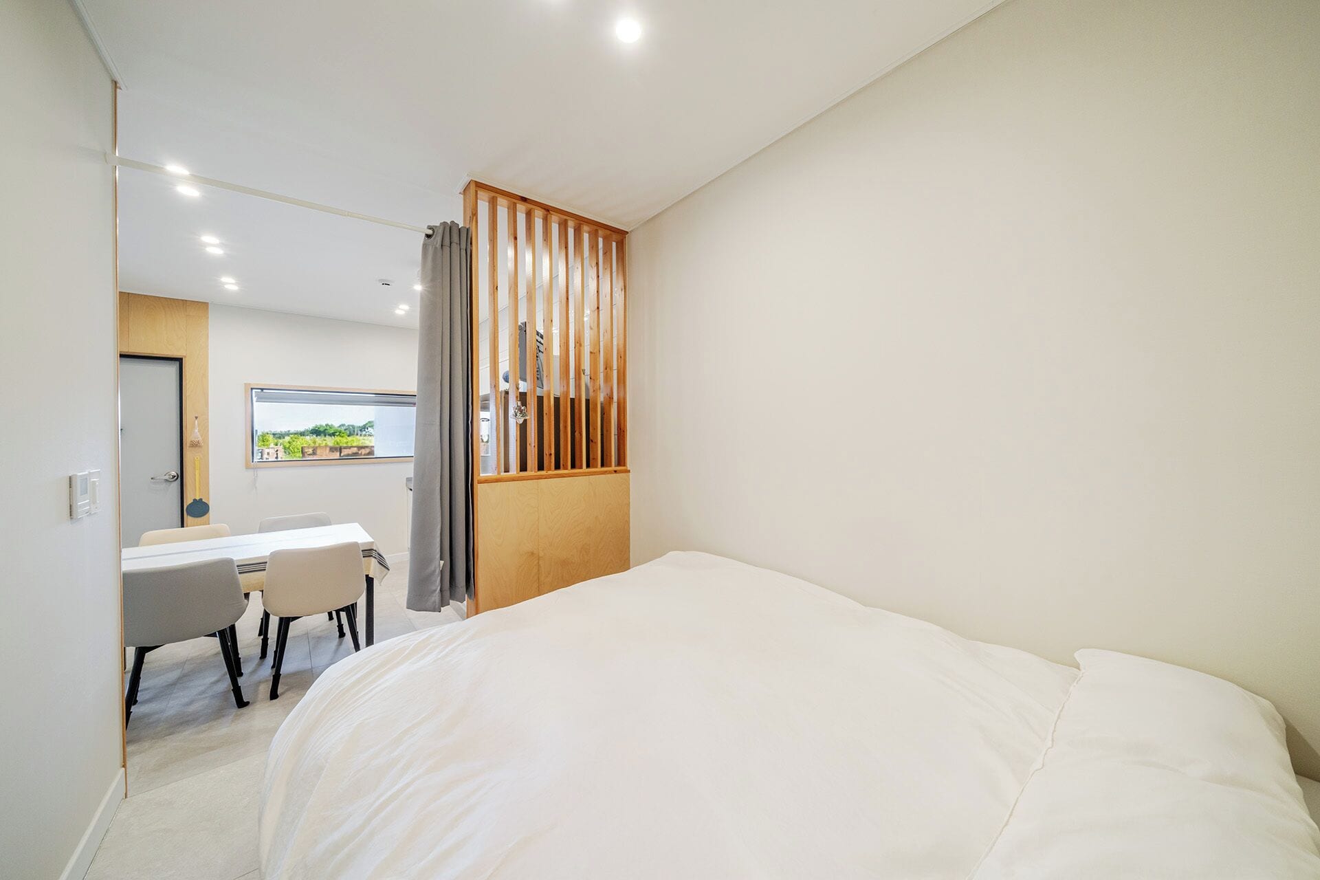 Un dormitorio con una cama grande, un escritorio con sillas y vistas a la vegetación a través de una ventana.