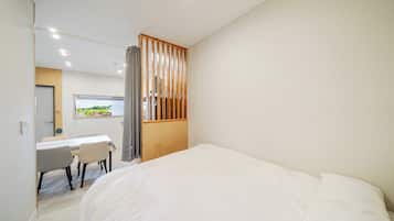 Un dormitorio con una cama grande, un escritorio con sillas y vistas a la vegetación a través de una ventana.