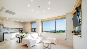A modern living room with a sofa, a small table, and a view of the outdoors. - Gyeongju Sanmaru Pension (Gyeongju)