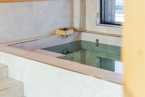 Een moderne badkamer met een douche met glazen wand, een houten medicijnkastje en een raam voor natuurlijk licht.