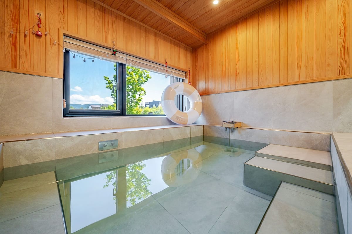 Une piscine intérieure moderne dotée d’un plancher en verre transparent, de murs en bois et offrant une vue sur l ’extérieur.